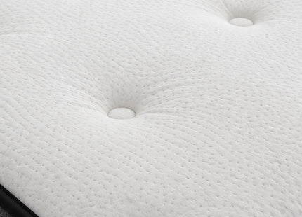 Close-up of a white tufted mattress or cushion surface with buttoned depressions and a black edge visible along the bottom.