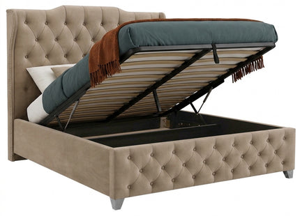 A tufted ottoman storage divan bed in beige fabric, shown with the mattress lifted open to reveal the storage compartment underneath. The bed features a high button-tufted headboard and footboard, with a teal mattress and a brown throw blanket visible.